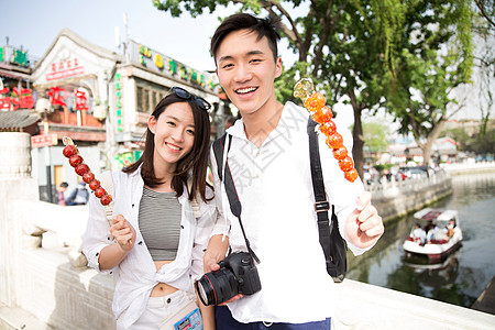 青年情侣旅游拿着糖葫芦高清图片