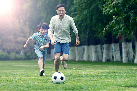 家庭健康快乐父子在草地上踢足球背景
