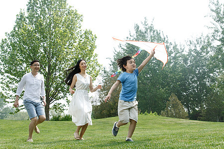 跑爱30多岁一家三口在草地上放风筝图片