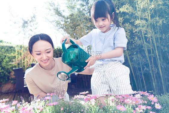 年轻的母亲和女儿在浇花图片