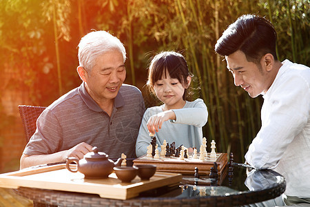 快乐祖孙三代在庭院里下棋图片