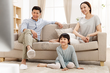 家庭幸福的一家三口在客厅看电视图片
