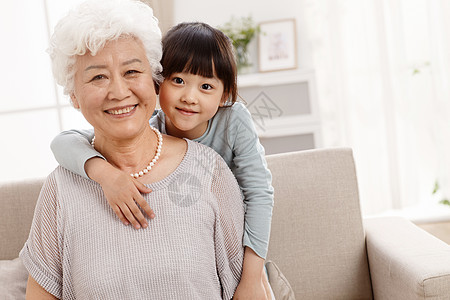 亚洲老年女人注视镜头可爱的小女孩和祖母在客厅图片