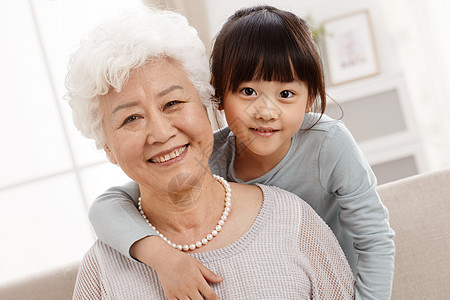 老年女人愉悦享乐可爱的小女孩和祖母在客厅图片