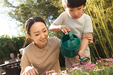 母亲和儿子在花园里浇花图片
