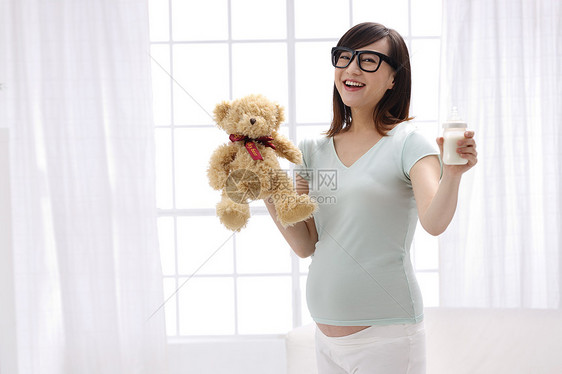 彩色图片满意微笑孕妇手拿玩具熊及奶瓶图片