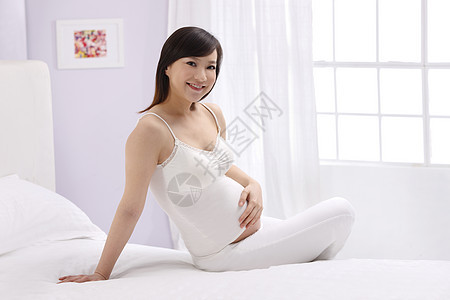 水平构图亚洲幸福孕妇坐在床上图片