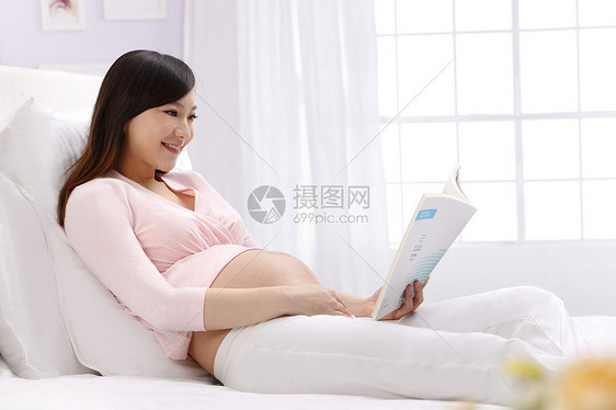 女人休闲轻松孕妇坐在床上看书图片