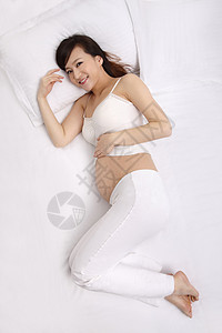 全身像垂直构图怀孕的孕妇躺在床上图片