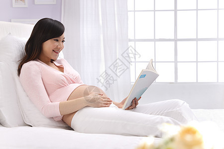 身体保养侧面视角爱孕妇坐在床上看书图片