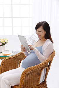 摄影微笑东亚孕妇看平板电脑图片