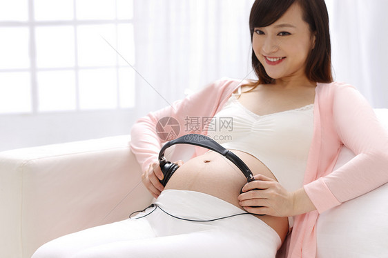 仅女人爱健康生活方式孕妇把耳机放在肚子上图片
