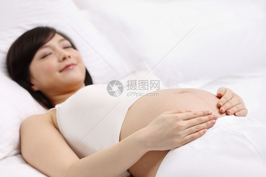 侧面视角健康的孕育孕妇躺在床上睡觉图片
