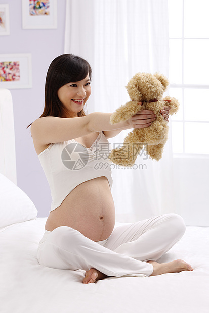 亚洲住宅房间仅女人孕妇拿着玩具熊图片