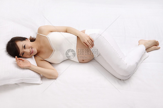 健康生活方式注视镜头幸福孕妇躺在床上图片