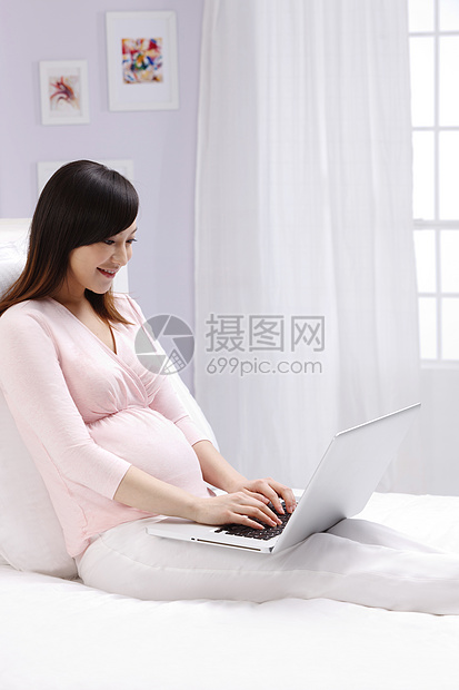 青年女人时尚孕育孕妇使用笔记本电脑图片