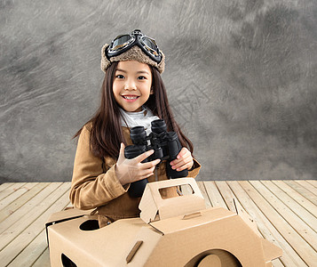 坐在纸飞机里的快乐女孩拿着望远镜图片