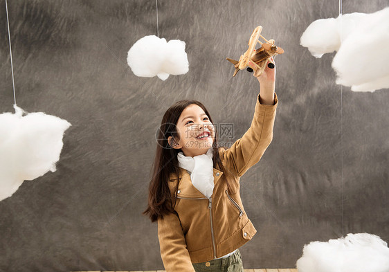微笑的儿童快乐女孩拿着飞机模型图片