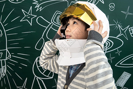 火箭上人戴着航天员头盔的小男孩站在黑板前背景