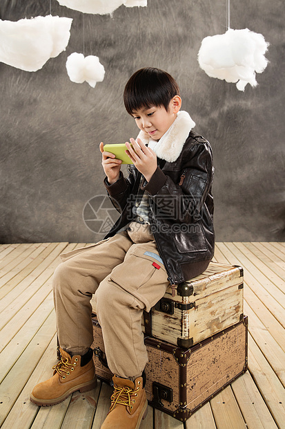 室内6岁到7岁灵感小男孩坐在复古行李箱上玩游戏机