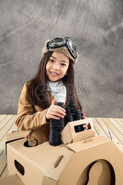 室内坐在纸飞机里的快乐女孩拿着望远镜图片