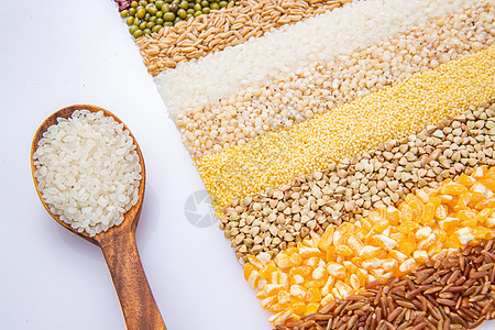 绿色食品稻谷五谷杂粮平铺和盛满大米的木匙图片