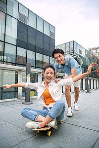 青年学生年轻男子向前推着坐在滑板上的女友图片