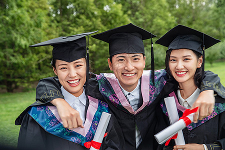 毕业我们在一起户外三个穿着学士服的大学生搂在一起背景