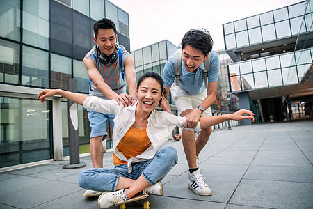 滑板运动年轻男子向前推着坐在滑板上的女同学高清图片