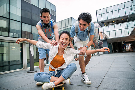 滑板运动年轻男子向前推着坐在滑板上的女同学图片