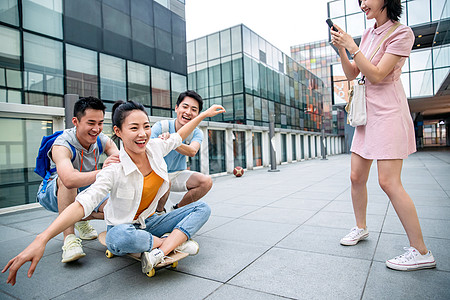 年轻男子向前推着坐在滑板上的女同学图片