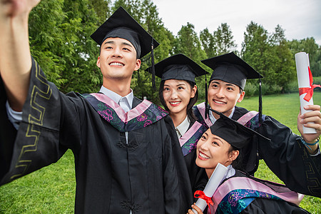 微笑的表情高等教育四个身穿学士服的大学生扶着镜头一起自拍背景