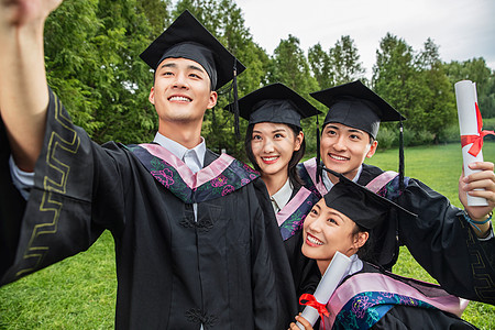 面部表情高等教育休闲活动四个身穿学士服的大学生扶着镜头一起自拍图片