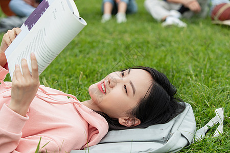 女孩在草坪读书女大学生躺在草地上看书背景