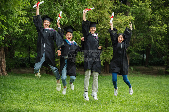 草地大学生穿着学士服庆祝毕业图片