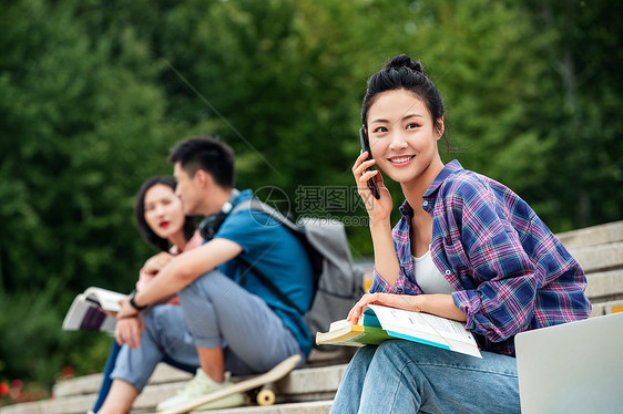 教育笑乐趣快乐的大学生坐在台阶上打电话图片