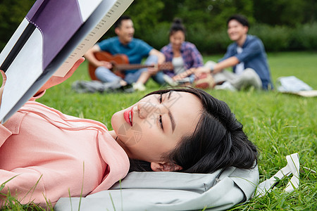 躺在草地上青年女大学生在草地上享受课余时间背景