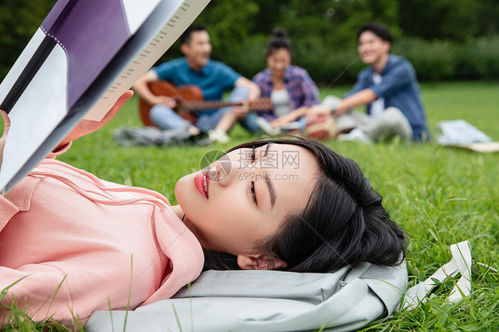 青年女大学生在草地上享受课余时间图片