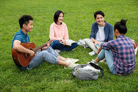 快乐的大学生在草地上弹吉他唱歌图片