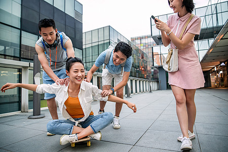 年轻男子向前推着坐在滑板上的女同学图片