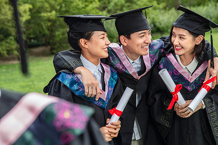 户外穿着学士服的大学生快乐的搂在一起图片