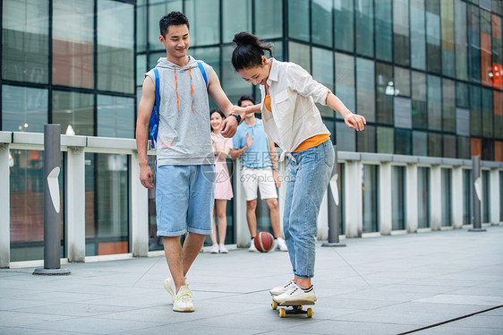 帅气的大学生教女朋友滑滑板图片