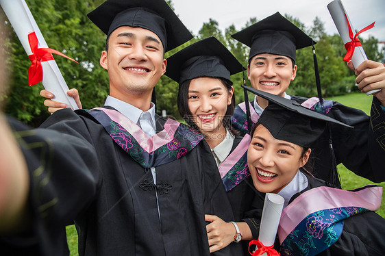 四个身穿学士服的大学生一起自拍图片