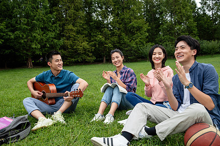 课外活动社交全身像快乐的大学生在草地上弹吉他唱歌图片
