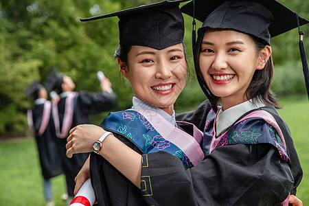 户外穿着学士服的大学生激动的拥抱在一起高清图片