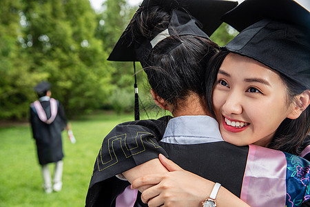 毕业我们在一起户外穿着学士服的大学生拥抱在一起背景