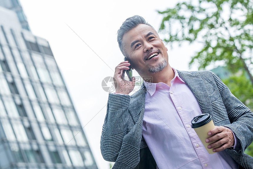 中老年商务男士拿着咖啡杯打电话图片