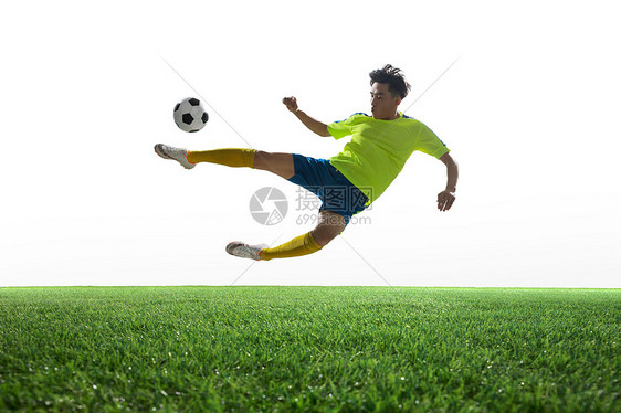 草地一名男足球运动员踢球图片