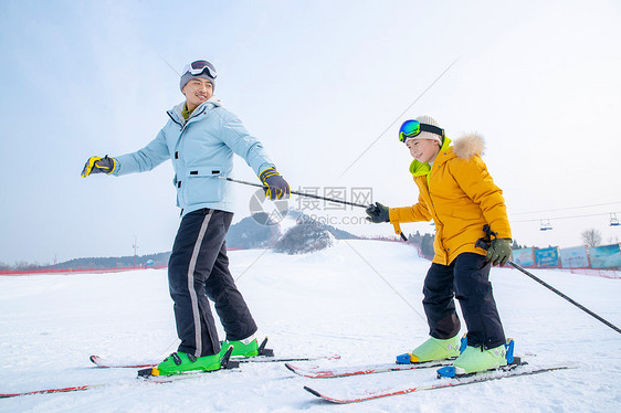 手套滑雪杖青年男人滑雪场上滑雪的快乐父子图片