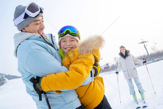滑雪场上抱在一起的父子和滑雪的母亲图片